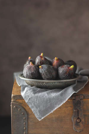 Black fresh figs in a metalic plate on dark background. Copy spaceの写真素材