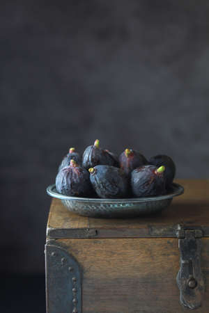 Black fresh figs in a metalic plate on dark background. Copy spaceの写真素材