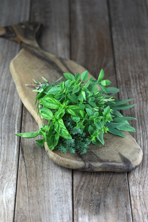 Fresh herb bouquet with rosemary, thyme, mint, sage and different kind of basil. Farm-to market herbs and sprigs tied with string in a bouquet on wooden background.の写真素材