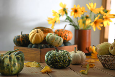 Autumn composition of little pumpkins and bouquet of yellow flowers on wooden background.の写真素材