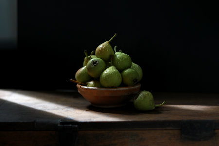 Bowl with ripe pears on wooden table against dark background. Space for textの写真素材