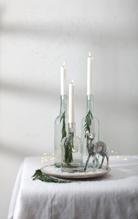 Simple Christmas, New Year composition, centrepiece with candles and deer on the table.の写真素材