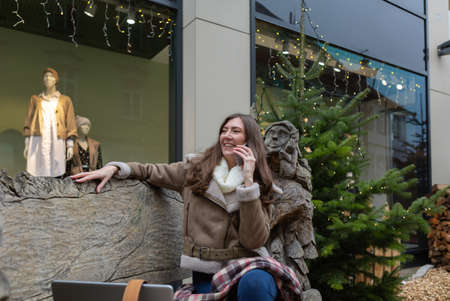 Young woman happy sitting on a bench and talking via phoneの写真素材
