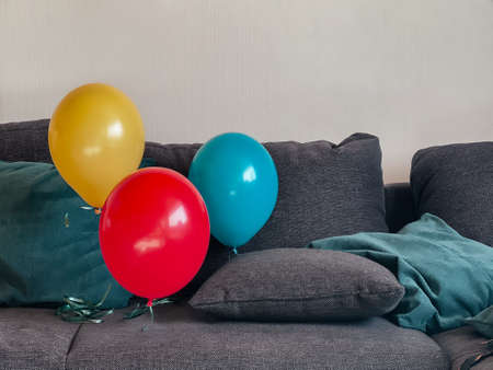 Three balloons yellow red and blue floating above the couchの写真素材