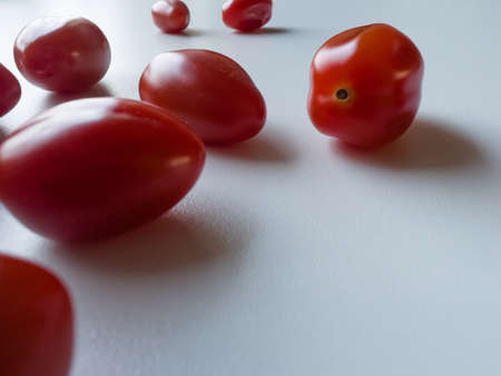 Cherry tomatoes are lying on a white table, space for a textの写真素材