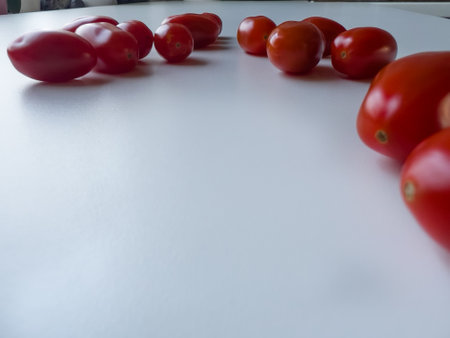 Cherry tomatoes are lying on a white table, space for a textの写真素材
