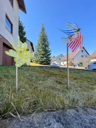 Two colorful pinwheel with houses in the backgroundの写真素材
