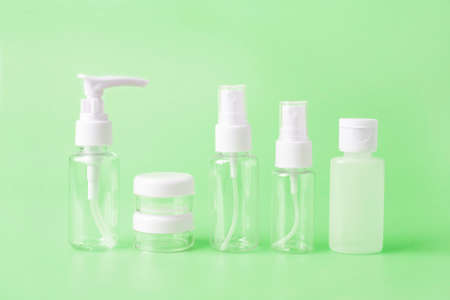 Set of empty travel women toiletries beauty kit on vivid green background. Approved for airplane...
