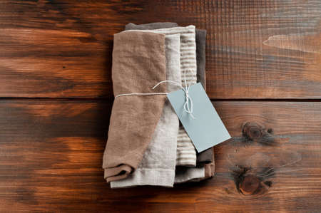 Heap of linen cotton napkins fabric on wood table background. Different colors brown, gray and striped. Food photo props.の写真素材