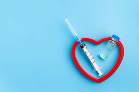 Heart Injection And Vaccine Vial. Covid 19 Cure. Medical Ampoule Dose And Needle On Blue Background