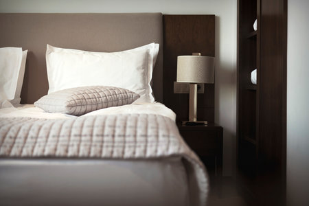 Made Up Bed In Room And Reading Lamp Selective Focus. Comfortable King Size Bedroom With Cotton Pillow And Gray Quilt Blanket. Business Trip In Hotel Concept.の写真素材