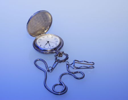 pocket watch with watch-chain on blue lightの写真素材