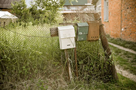 Vintage rustic mailboxes of different colors pinned on a fence. floating focusの写真素材