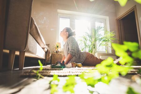 Beautiful woman doing yoga at home in sunny day. Crystal and aroma stick burn.の写真素材
