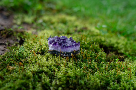 Beauterful purple ametist crystal close up on natural forest green moss background. Spiritual esoteric practice, magic healing rock for reiki crystal ritual.の写真素材