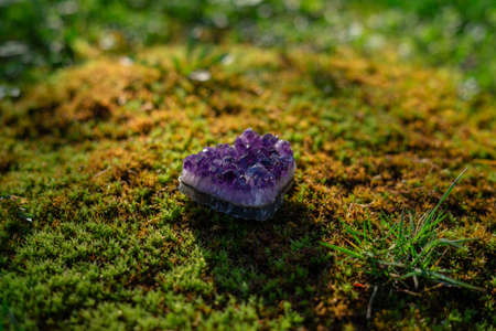 Beauterful purple ametist crystal close up on natural forest green moss background. Spiritual esoteric practice, magic healing rock for reiki crystal ritual.の写真素材