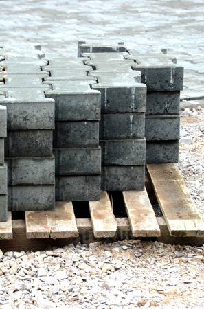 Grey concrete h-blocks on pallet. Sidewalk and gravel in the backgroundの写真素材