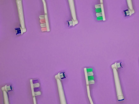 A lot of toothbrushes lie on purple background with copy space. Top view, flat lay. Minimal concept