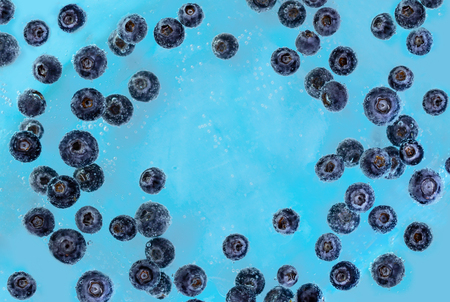 Blueberries sinking into blue water with air bubbles background.の写真素材