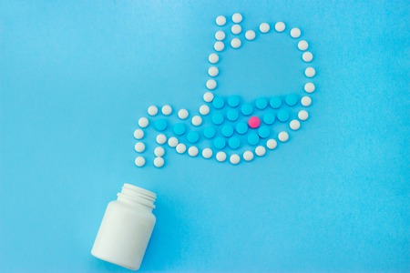Stomach made of white pills with some red and blue pills inside.の写真素材