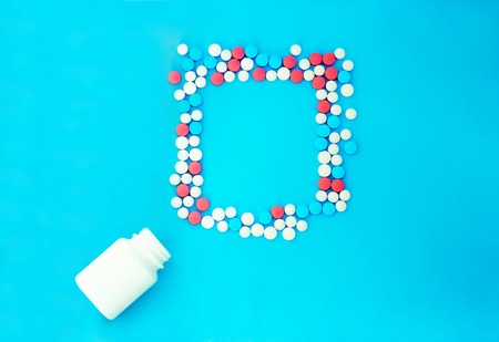 Multicolored pills on blue background with copy space. Medical concept. Flat lay. Top viewの写真素材