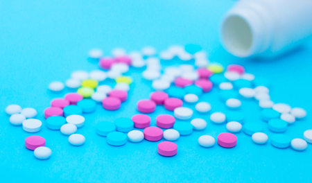 Multicolored pills on blue background with copy space. Medical concept. Flat lay. Top viewの写真素材