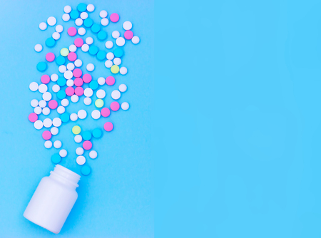 Multicolored pills on blue background with copy space. Medical concept. Flat lay. Top viewの写真素材