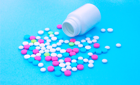 Multicolored pills on blue background with copy space. Medical concept. Flat lay. Top viewの写真素材