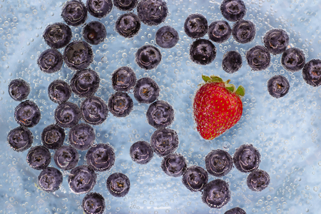 Ripe blueberries and strawberry in blue water with air bubbles. Top view. Wallpapersの写真素材