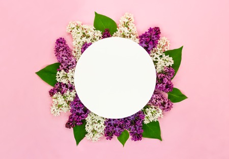 Beautiful lilac flowers and round blank card on light pink background. Syringa blossoms. Romantic summer greeting card. Top view. Copy space.の写真素材