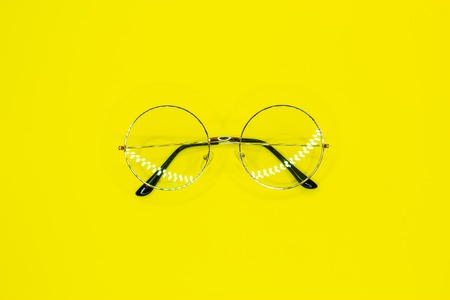 Round glasses on yellow background. Fashion accessory for a clear view. Top view.の写真素材