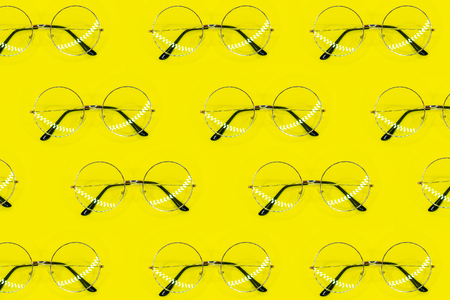Round sunglasses pattern on yellow background. Minimal summer pattern. Flat lay. Top view.の写真素材