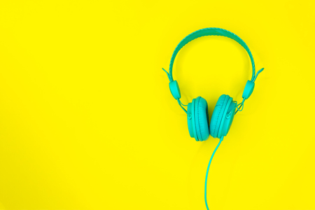 Turquoise or blue headphones or a computer headset on a yellow background with copy space. Top view.の写真素材