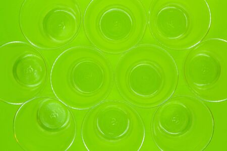 top view of disposable empty transparent plastic cups on green background. Recycling waste concept.の写真素材