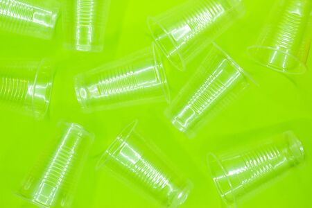 Disposable transparent plastic cups on a green background. Recycling ecology concept. Top view. Flat lay.の写真素材