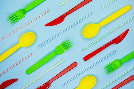 Multicolored plastic disposable tableware on light blue background. Top view. Flat lay.の写真素材