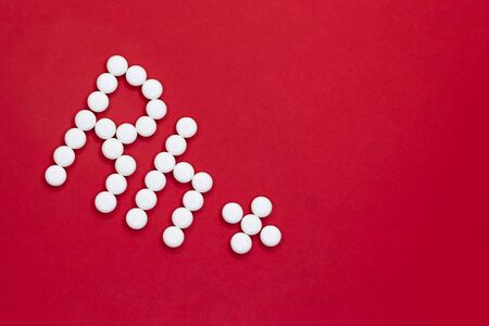 Positive Rh factor. Rh inscription made of white pills on a red background with copy space.