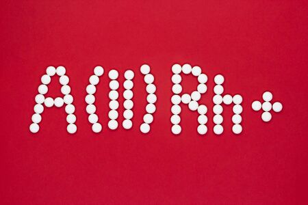 Second blood type. Blood type symbol from white pills on a red background. Blood type treatment. Top...