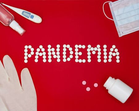 Text phrase Pandemia on a red background with medicines, hand antiseptic, thermometer and protective mask.の写真素材