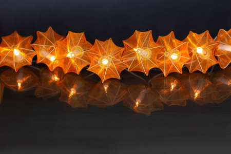 Electric garland of glowing pumpkins on a dark black background with copy space. Halloween border with flaming pumpkins and lights.の写真素材