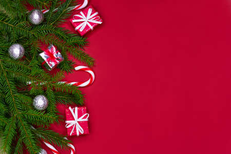Christmas decorations layout or flatlay with fir branches, gifts, balls and candy canes on red background with copy space.の写真素材