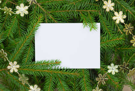 Christmas card on a background of fir branches and a garland of golden snowflakes. Flat lay. Nature New Year concept.の写真素材