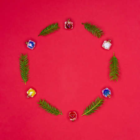 Holiday concept, New Year, greeting card. Creative composition of Christmas tree decorations and branches on a red background. Round decorative frame. Top view.の写真素材