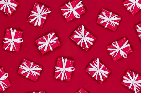 Pattern of gift boxes with white ribbons on a red background. Christmas flat lay.の写真素材