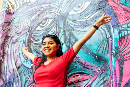Brunette woman with long hair dressed in white with her back to a wall-painted garden mural. art...