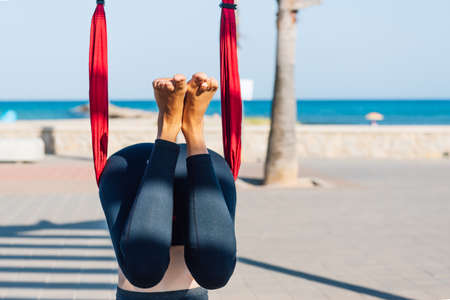 young woman doing yoga exercise on the ground outdoors by the sea at sunsetの写真素材