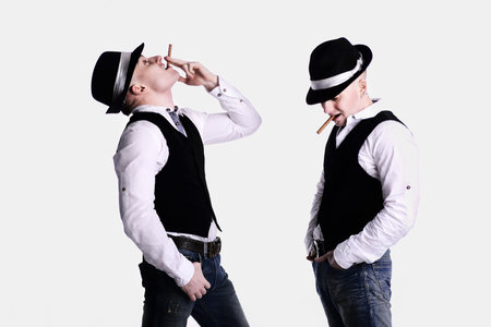 two twin brothers in gangster style posing. hats, vests, white shirts. white background.の写真素材