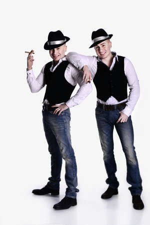 two twin brothers in gangster style posing. hats, vests, white shirts. white background.の写真素材