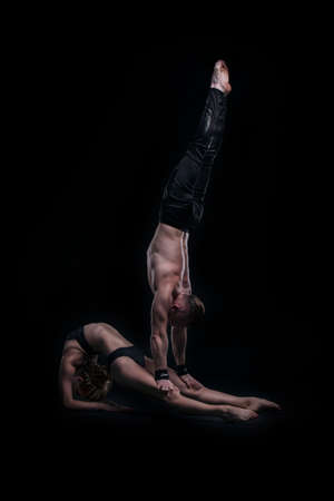 girl with boyfriend perform beautiful gymnastic elements. beautiful acrobatic couple. black backgroundの写真素材