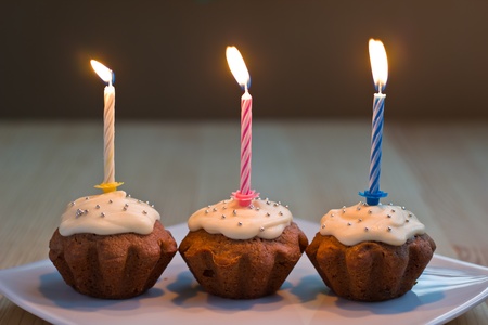 Three homemade muffins with burning candlesの写真素材